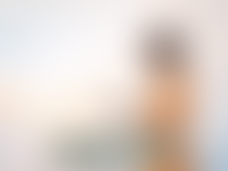 mulher negra com vestido laranja carregando algo como uma areia escura nas mãos