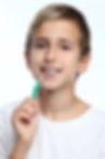 Un enfant avec un appareil dentaire et une brosse en main