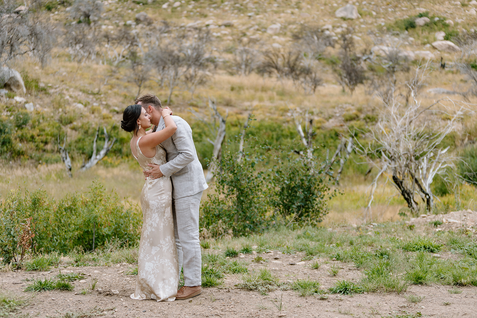 Brenna and Taylor embracing in a mountain meadow on their wedding day