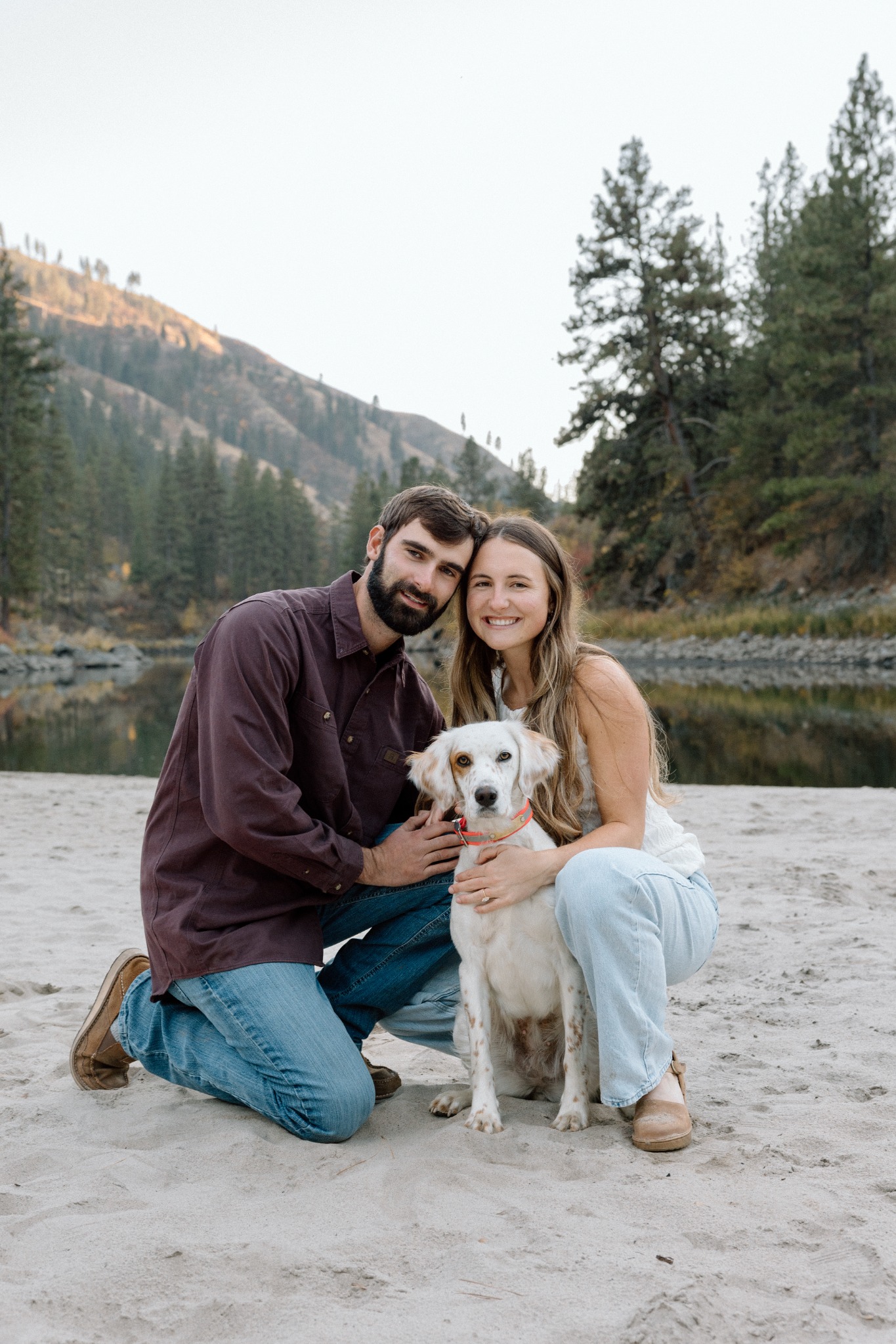 A couple sitting with their dog beside a mountain lake, photographed by Erin Bernius