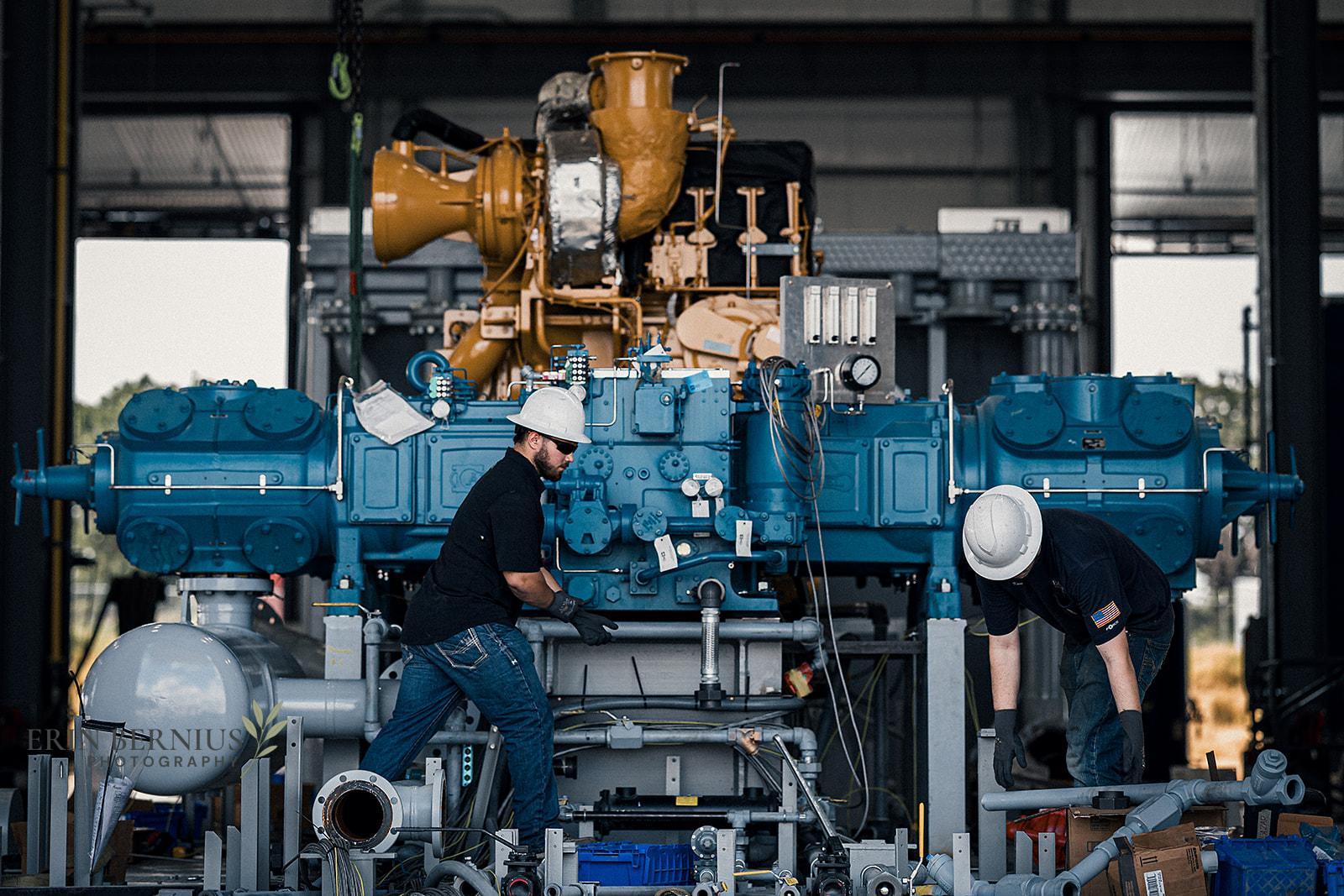 Two industrial workers working on equipment in a workshop, photographed by Erin Bernius