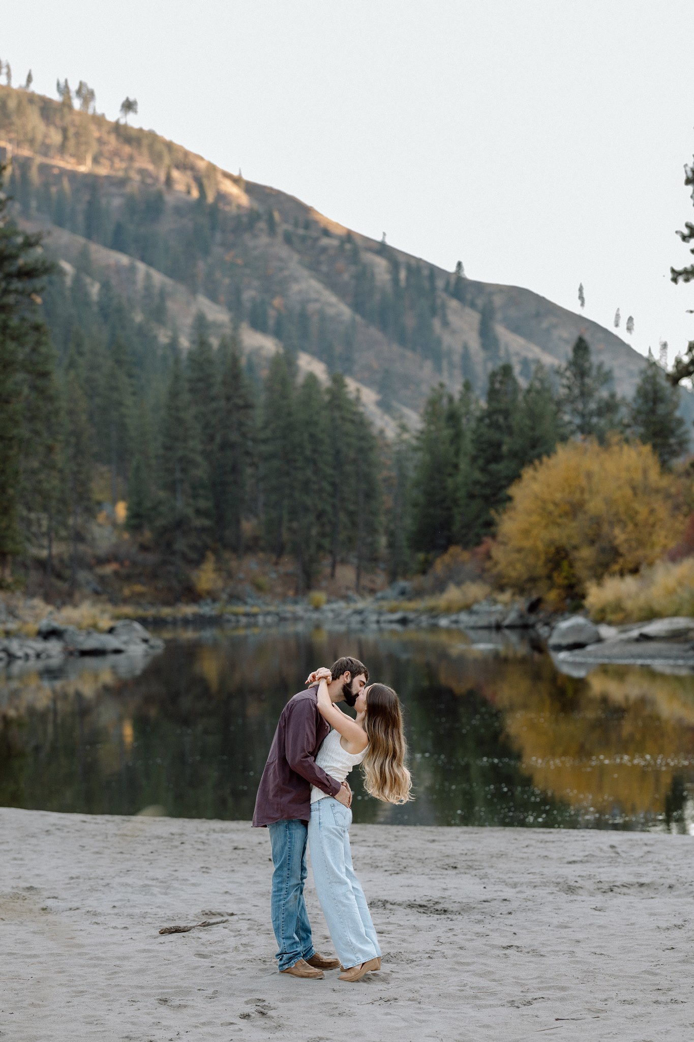 Olivia and Michael sharing a kiss beside an alpine lake