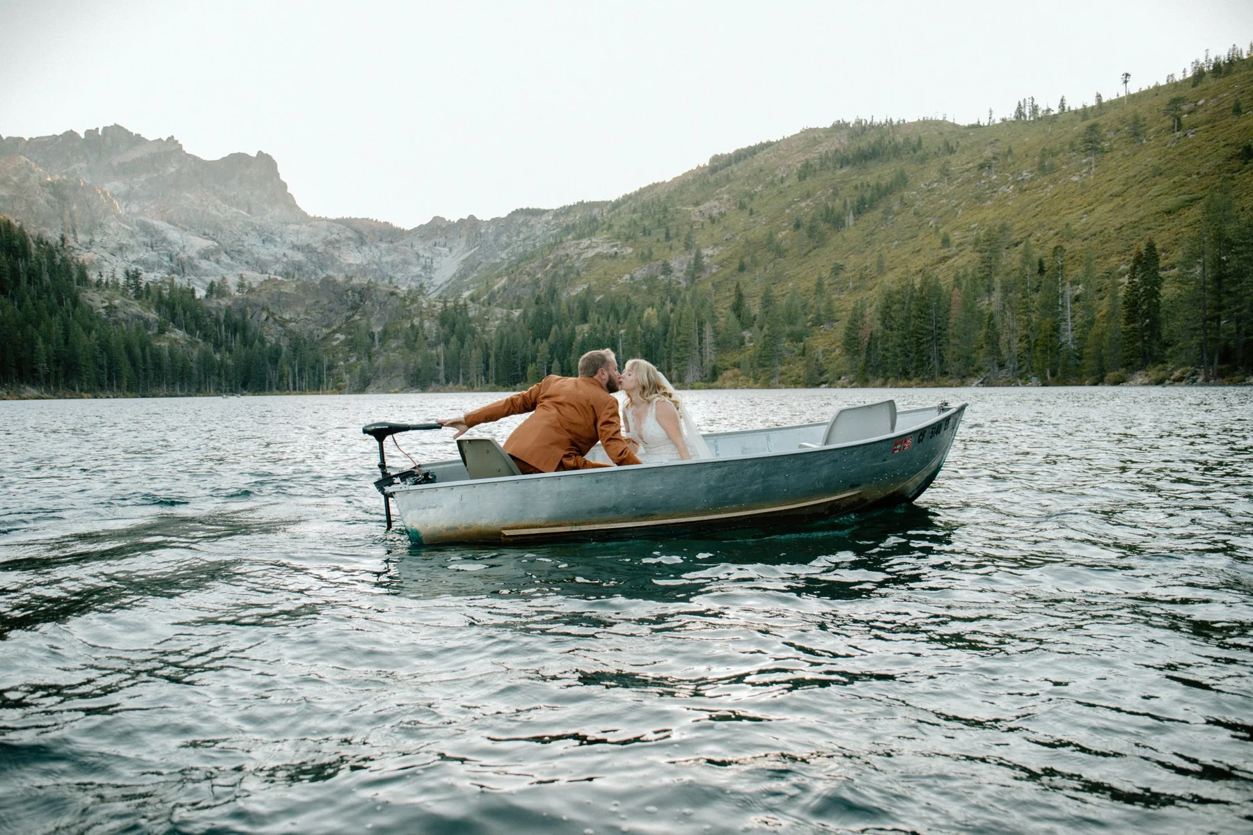 A newly married couple relaxing together in a rowboat on a mountain lake
