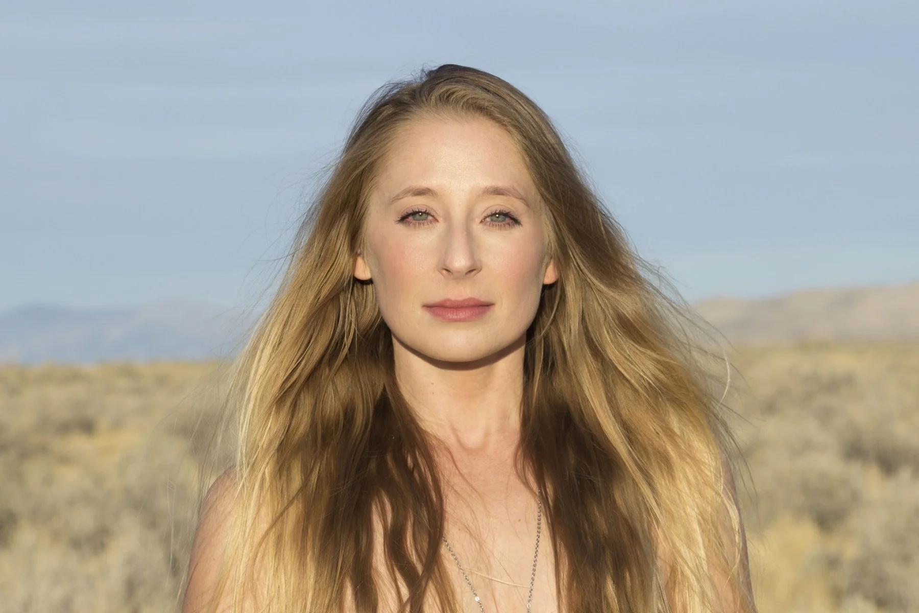 An outdoor headshot with a softly blurred landscape