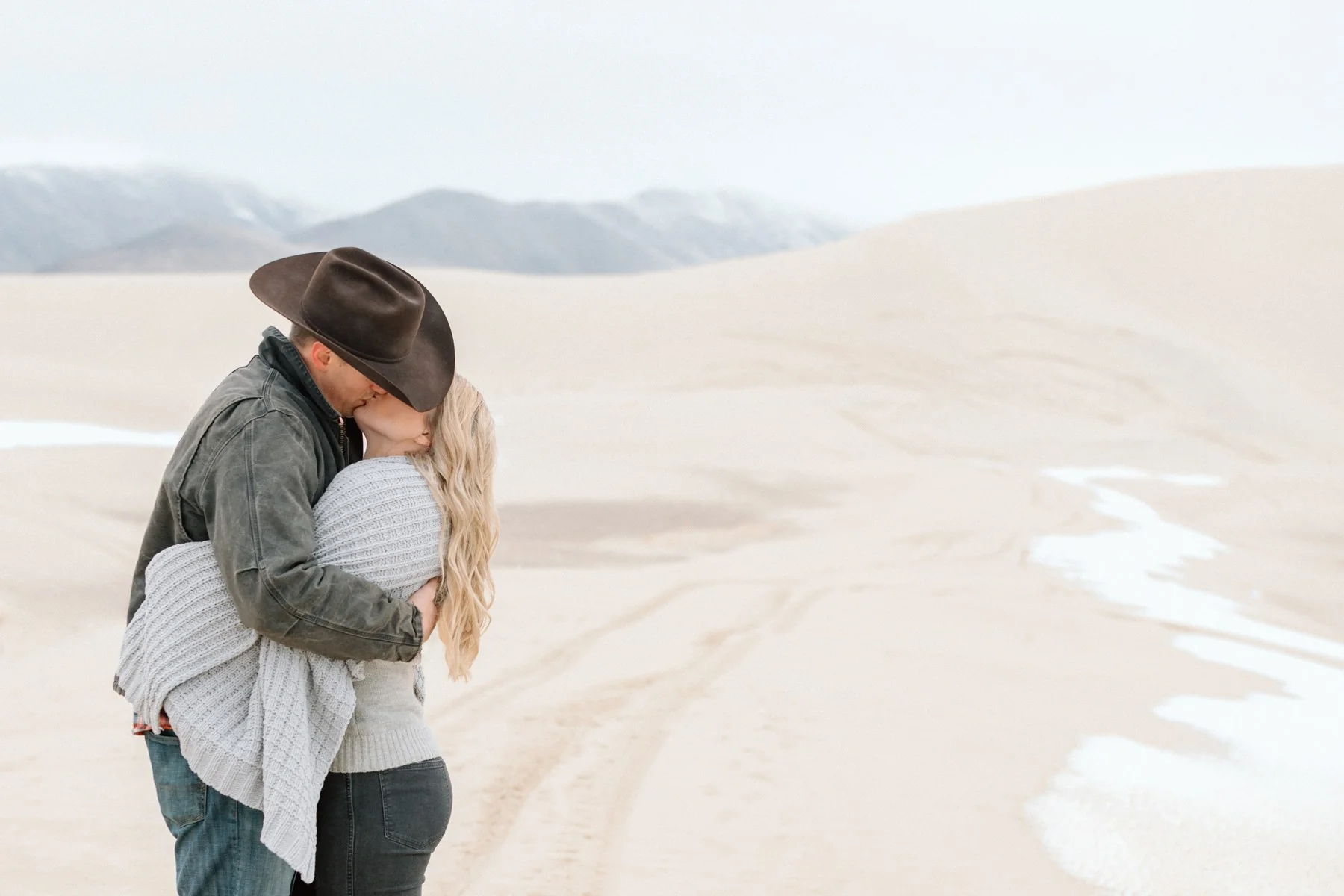 Couple embracing in soft afternoon light on sand dunes