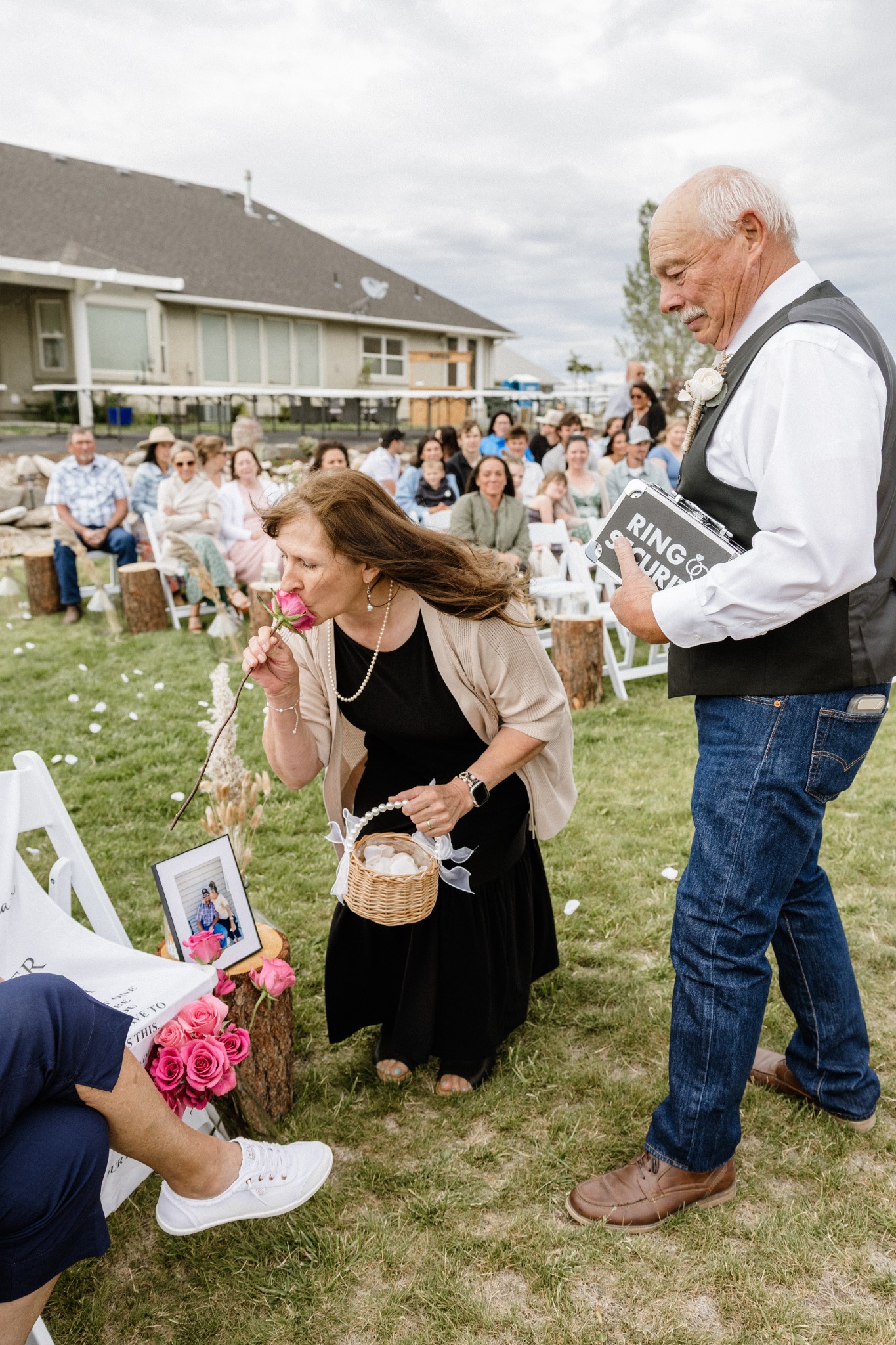 Two wedding participants sharing a playful moment in the aisle as guests look on