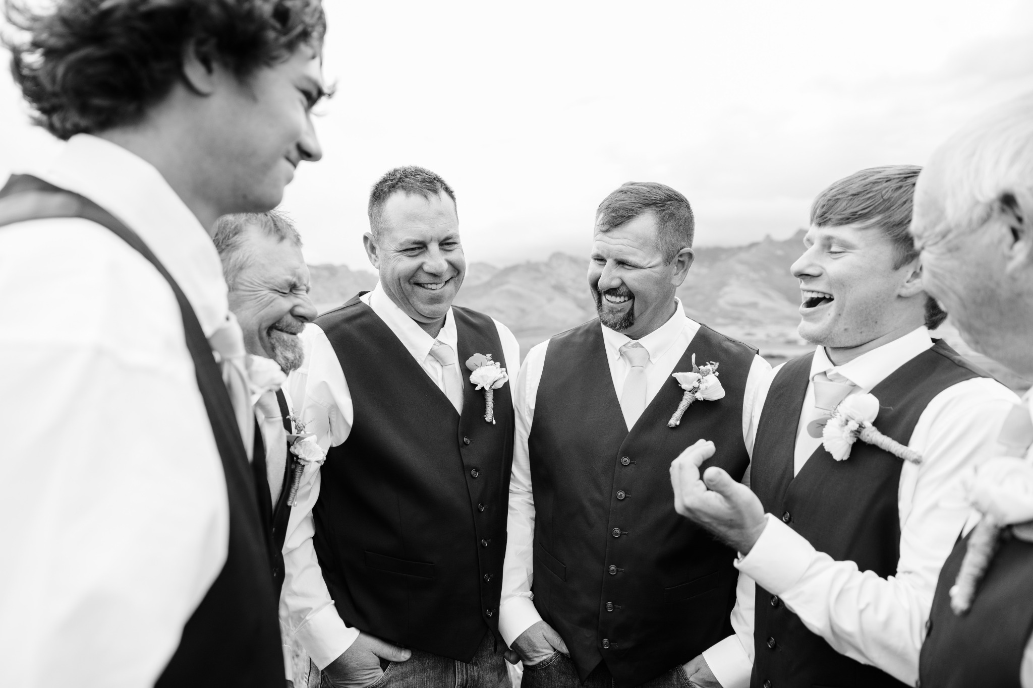 The groom and groomsmen sharing a laugh, photographed in black and white