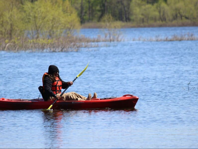 Person padding in the rier by themselves ina canoe