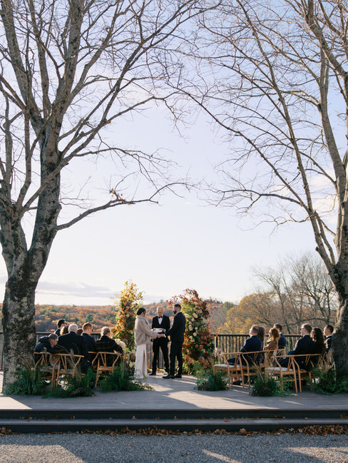 Bride and groom exchanging vows during an outdoor fall wedding ceremony with guests seated at a Connecticut estate venue