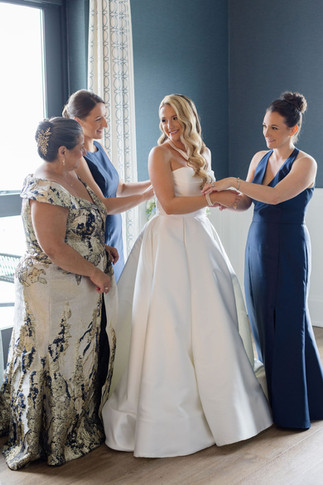 Bride in white bridal gown with bridesmaids in navy blue dresses Tyde at Walnut Beach wedding
