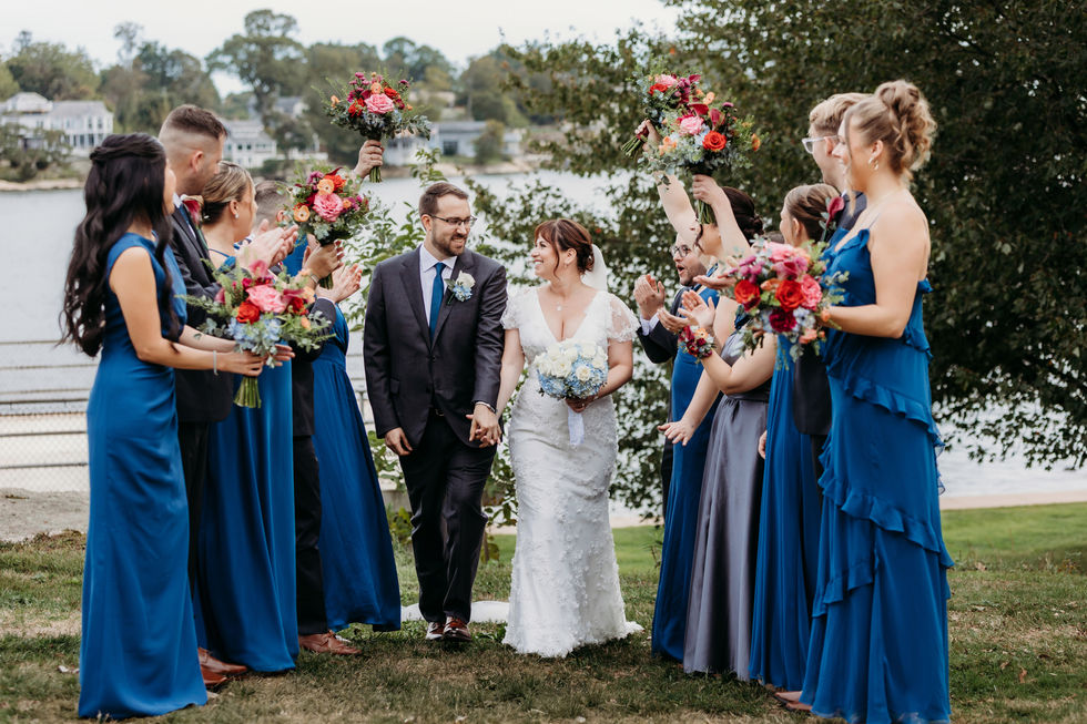 Woodwinds wedding with bride and groom walking through bridal party by the water