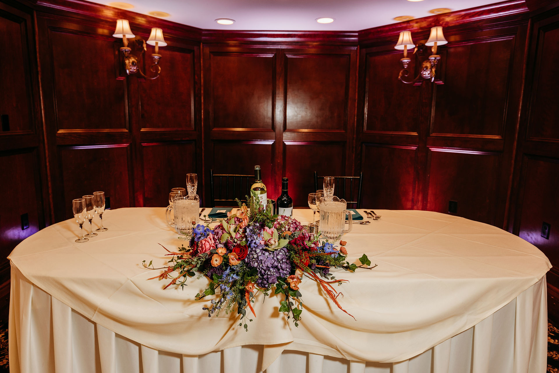 sweetheart table with jewel tone florals at wedding reception at the woodwinds