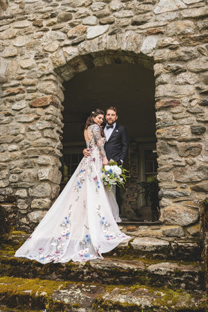 bride in floral wedding gown posed with groom in estate doorway
