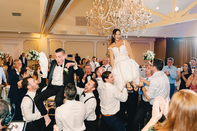 bride and groom lifted up on chairs at wedding reception