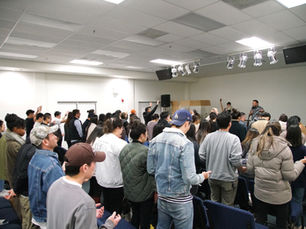A large group of people standing in prayer and worship at a Spirit-led church conference, receiving ministry during a powerful evening session.