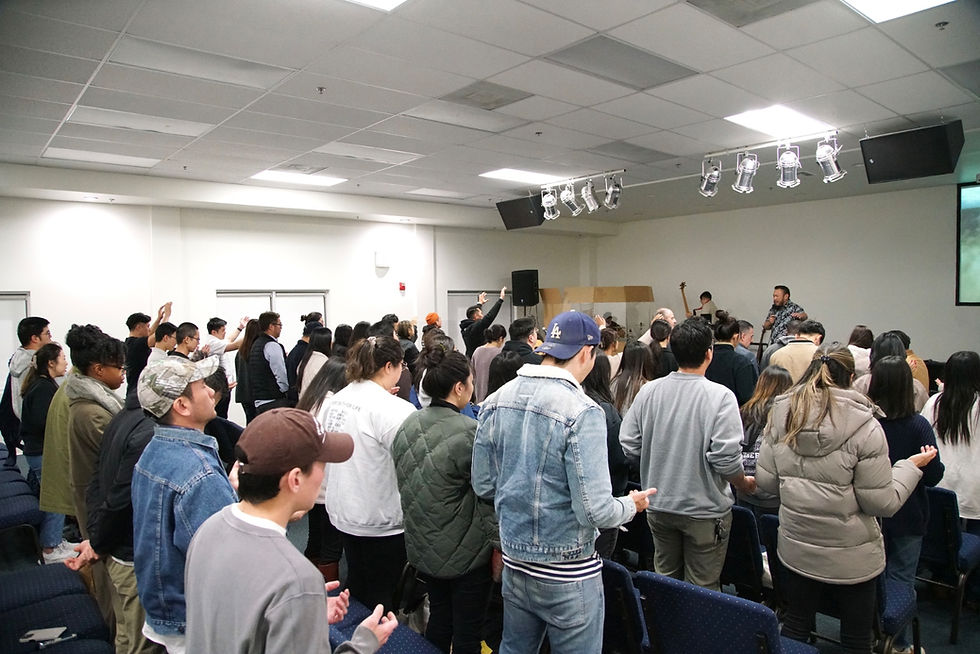 A large group of people standing in prayer and worship at a Spirit-led church conference, receiving ministry during a powerful evening session.