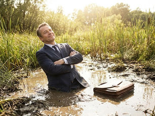 Businessman standing chest-deep in muddy water with briefcase on ground symbolizing being stuck in business without succession plan