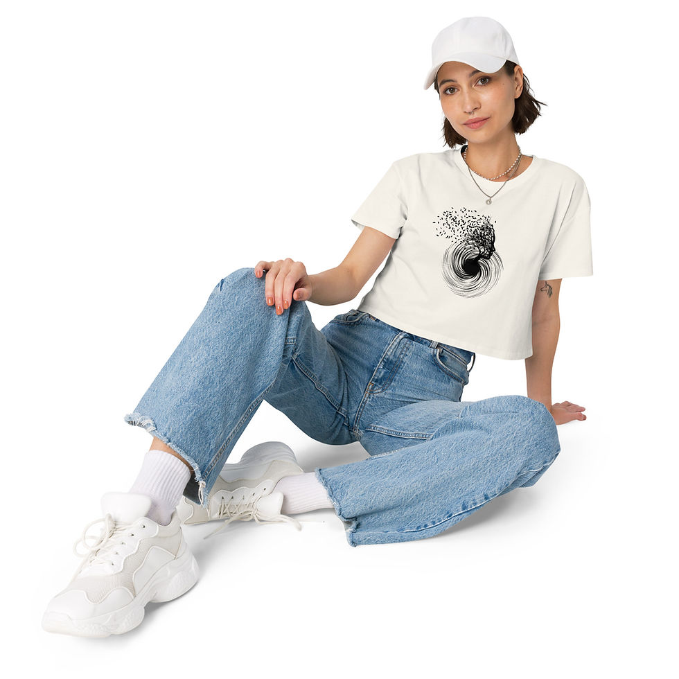 Thumbnail: Model sitting wearing the women’s crop top in Ecru, showing the ‘Grounded in the Vortex’ artwork.