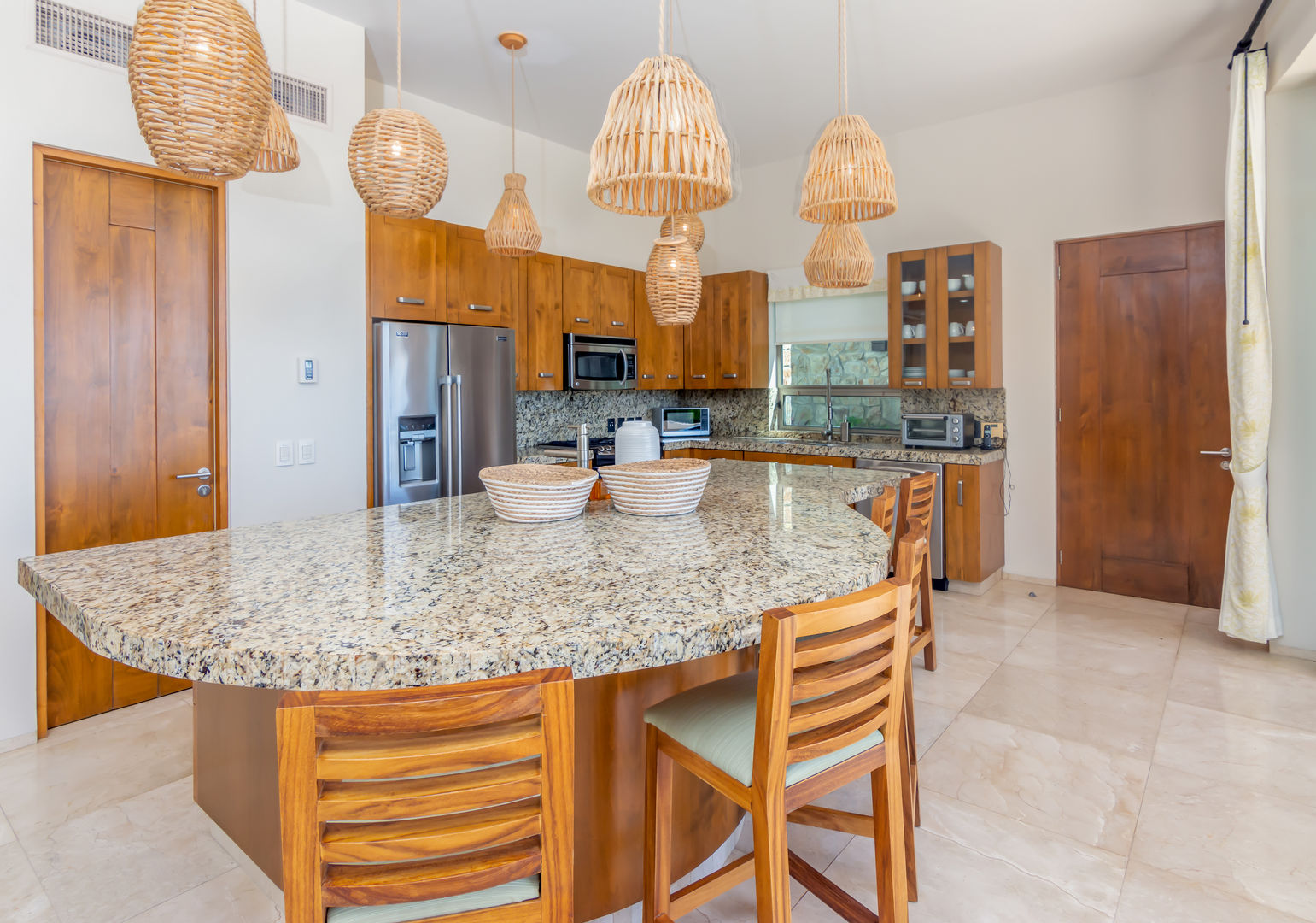 Kitchen with island and bar seating at Casa Kokomo Cabo