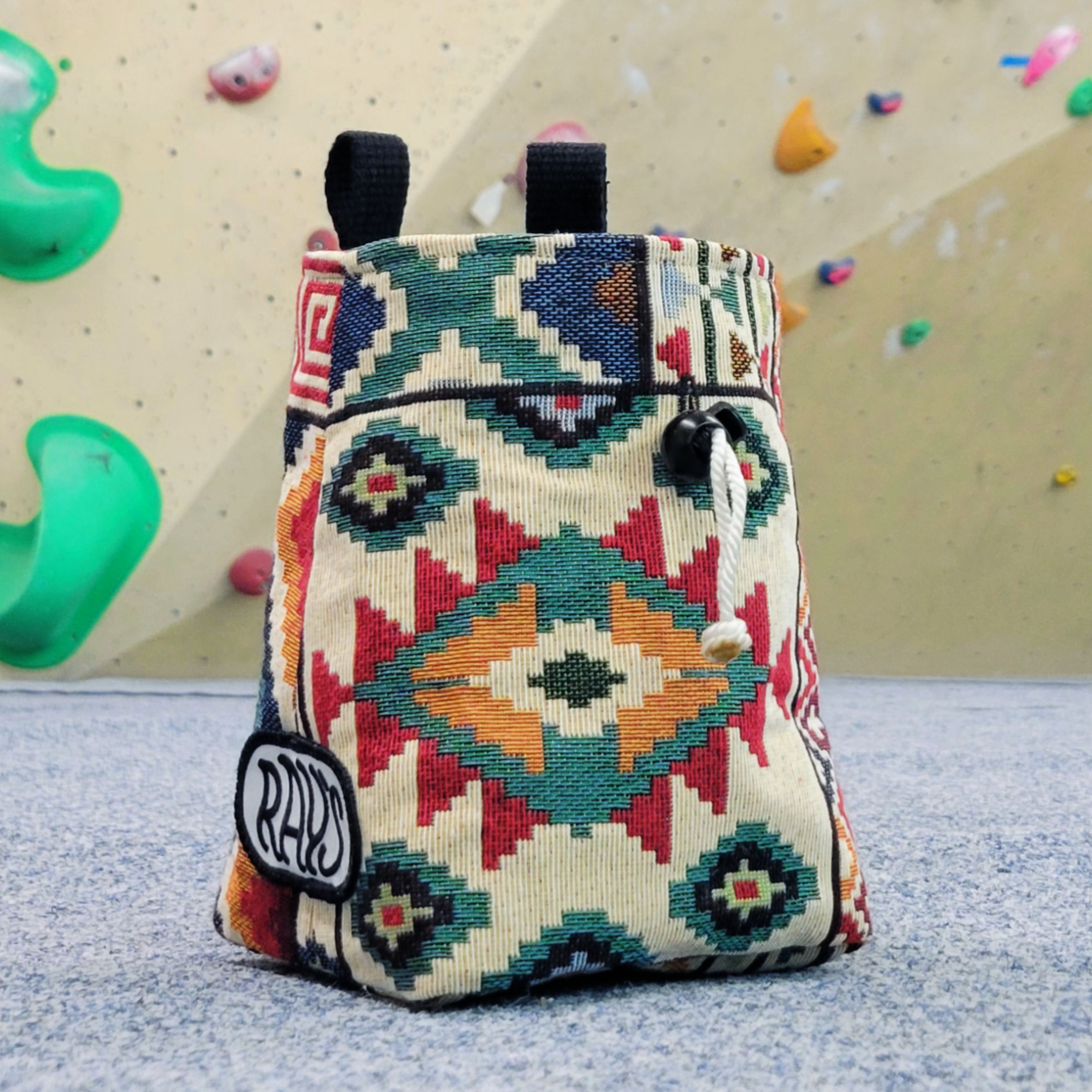 colourful apache patterned chalk bag sat in front of a climbing wall