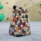 a unique chalk bag made from a colourful honeycomb tapestry sat in front of a climbing wall