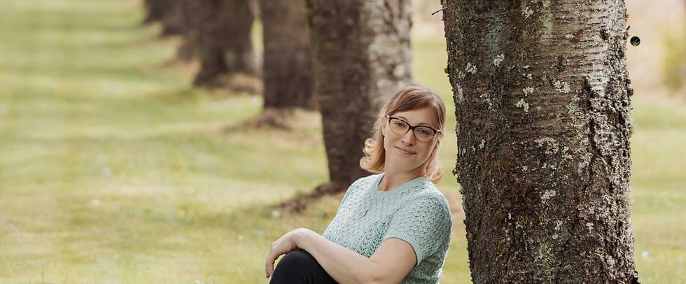 Jen Schmidt, embodiment and breathwork coach, seated on grass against a tree in Langley, BC - grounded and at peace