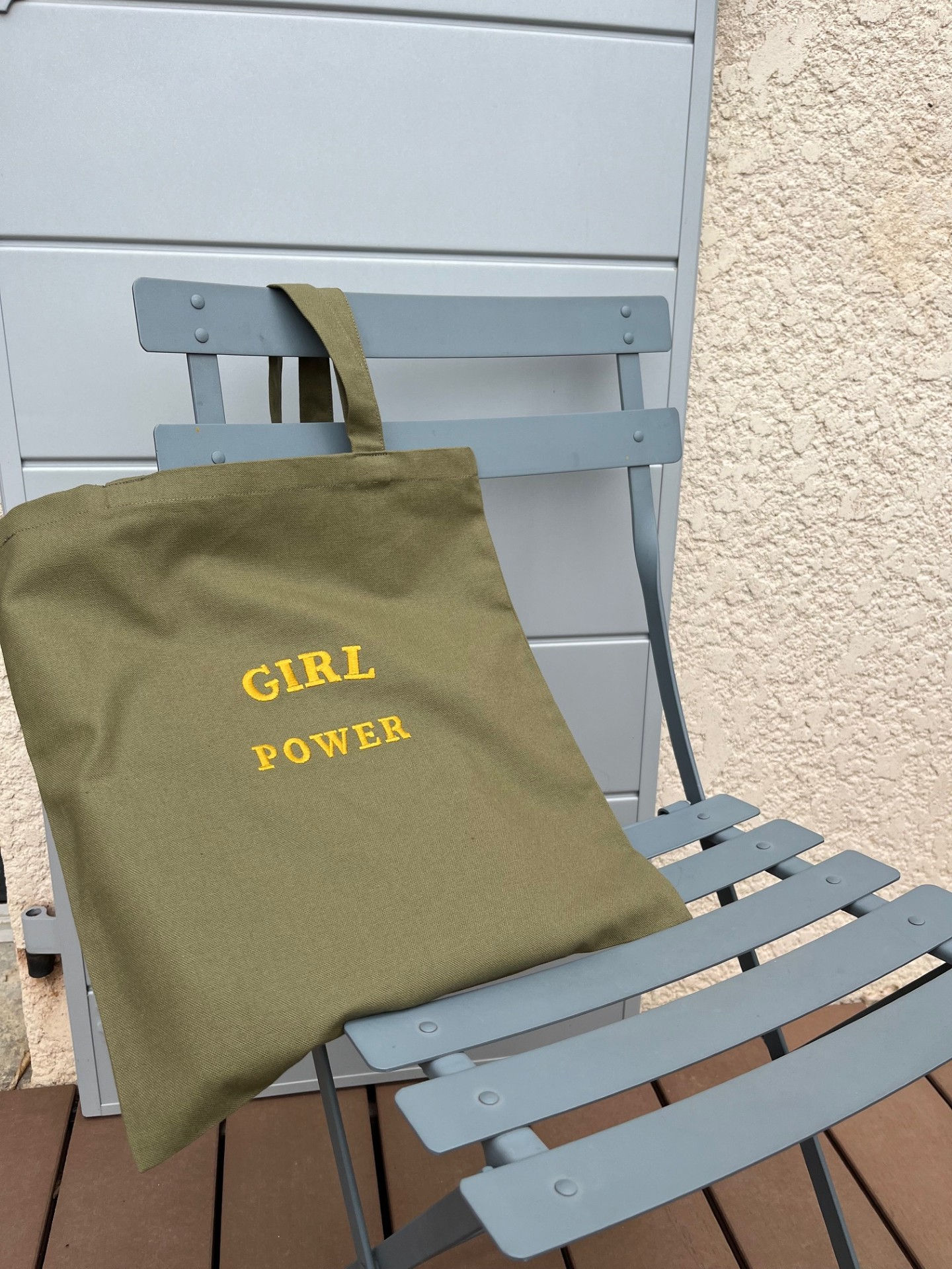Sac "tote bag" kaki brodé Girl Power posé sur une chaise