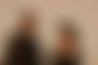 Close-up of a couple about to kiss at sunset, sun flare between them. The man wears sunglasses and a leather jacket, the scene feels romantic.