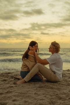 Woman and man at sunset by the beach. Warm, golden light and tranquil waves set a carefree, joyful mood.