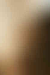 A woman in white leans on a man in a dark suit, seated in a rustic setting with flowers and a wooden table. Vintage, romantic mood.