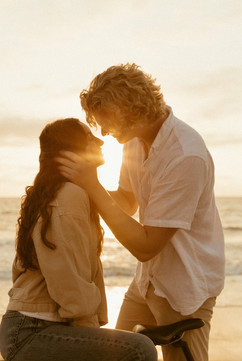 Woman and man ride a bike at sunset by the beach. Warm, golden light and tranquil waves set a carefree, joyful mood.