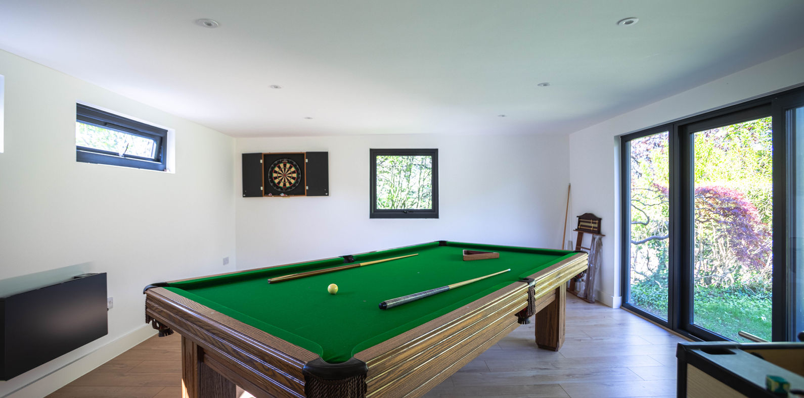 Stunning modern internal of a garden room in surrey, showing big sliding doors, windows, full size snooker table, dart board