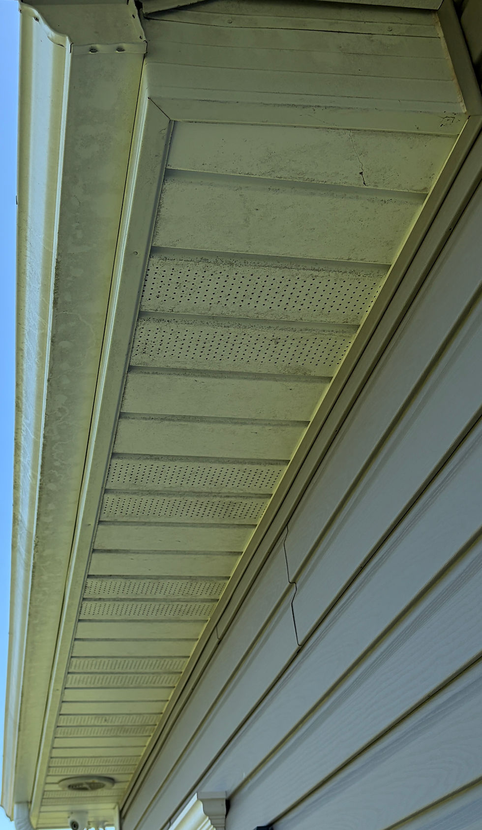 Dirty vinyl soffit with mold and algae buildup before soft washing in Sydney, NS