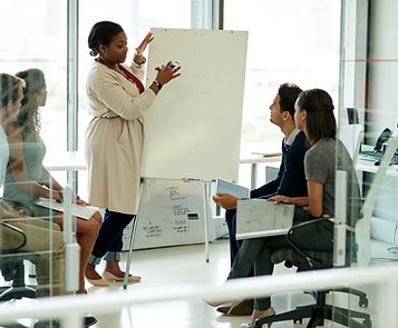 shutterstock_2697773425.jpg. Resilience coach presenting to a diverse group of legal professionals in a modern conference roo