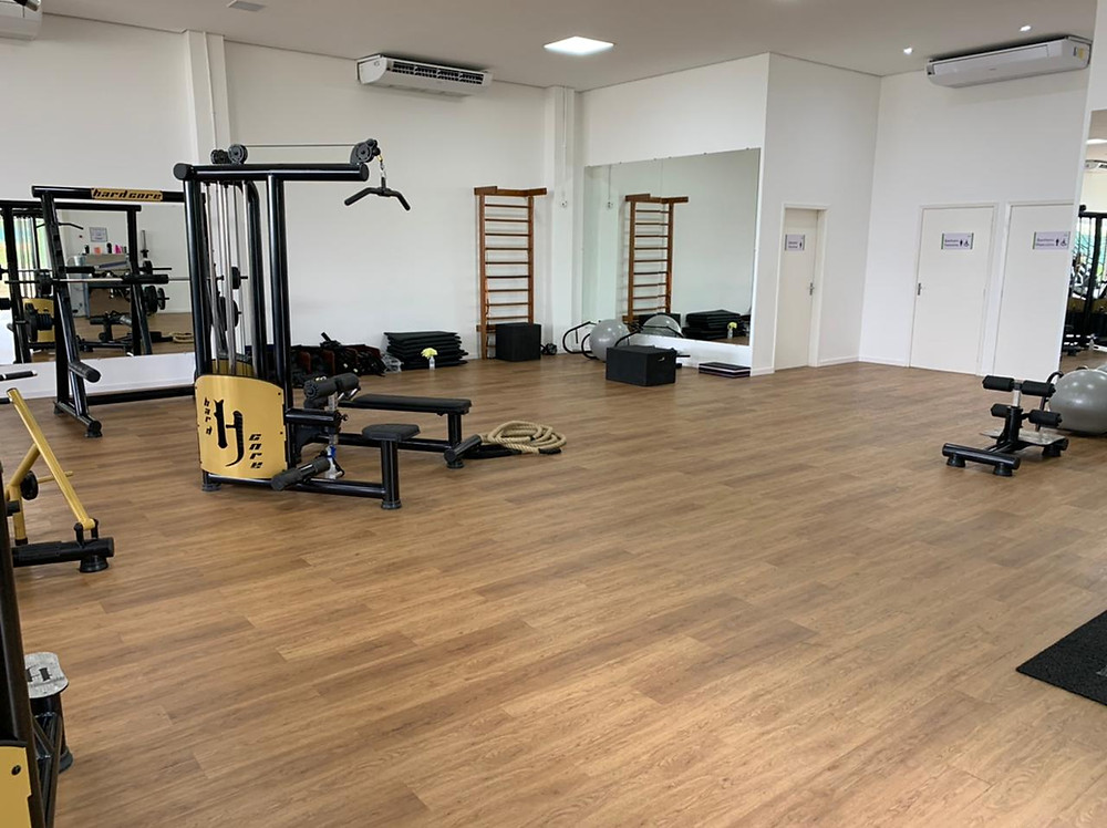 Piso amadeirado tonalidade clara, com equipamentos de academia