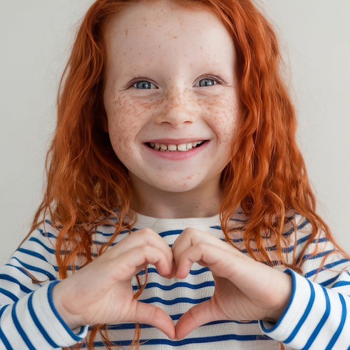 lovely-child-with-red-long-hr-freckles-smile-show-heart-sign-i-love-you-gesture-look-adora