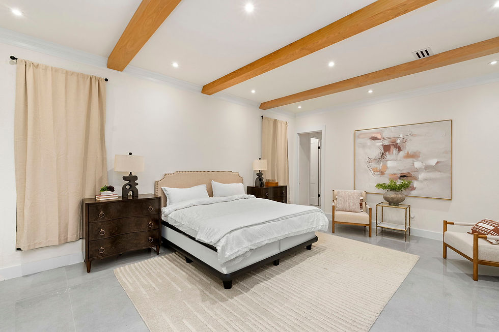 Neutral-toned bedroom with a wooden beam ceiling, white bed, dark wood nightstands, abstract painting, beige curtains, and soft lighting.