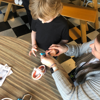 child practicing brushing teeth in a model of a mouth with hand-over-hand assistance
