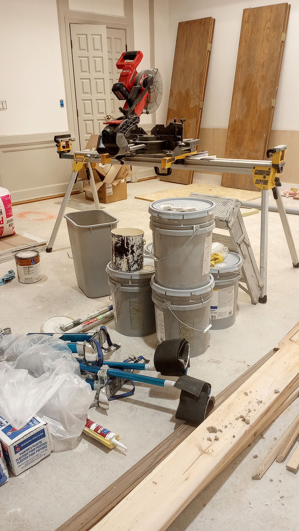 Renovation supplies, mainly a miter saw and paint buckets, sitting in a meeting room