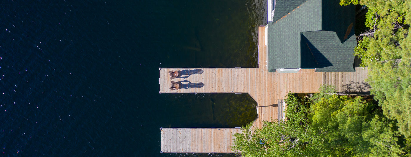 Aerial view of a cottage wooden pier on a lake in Muskoka, Ontario Canada. Two brown Adiro