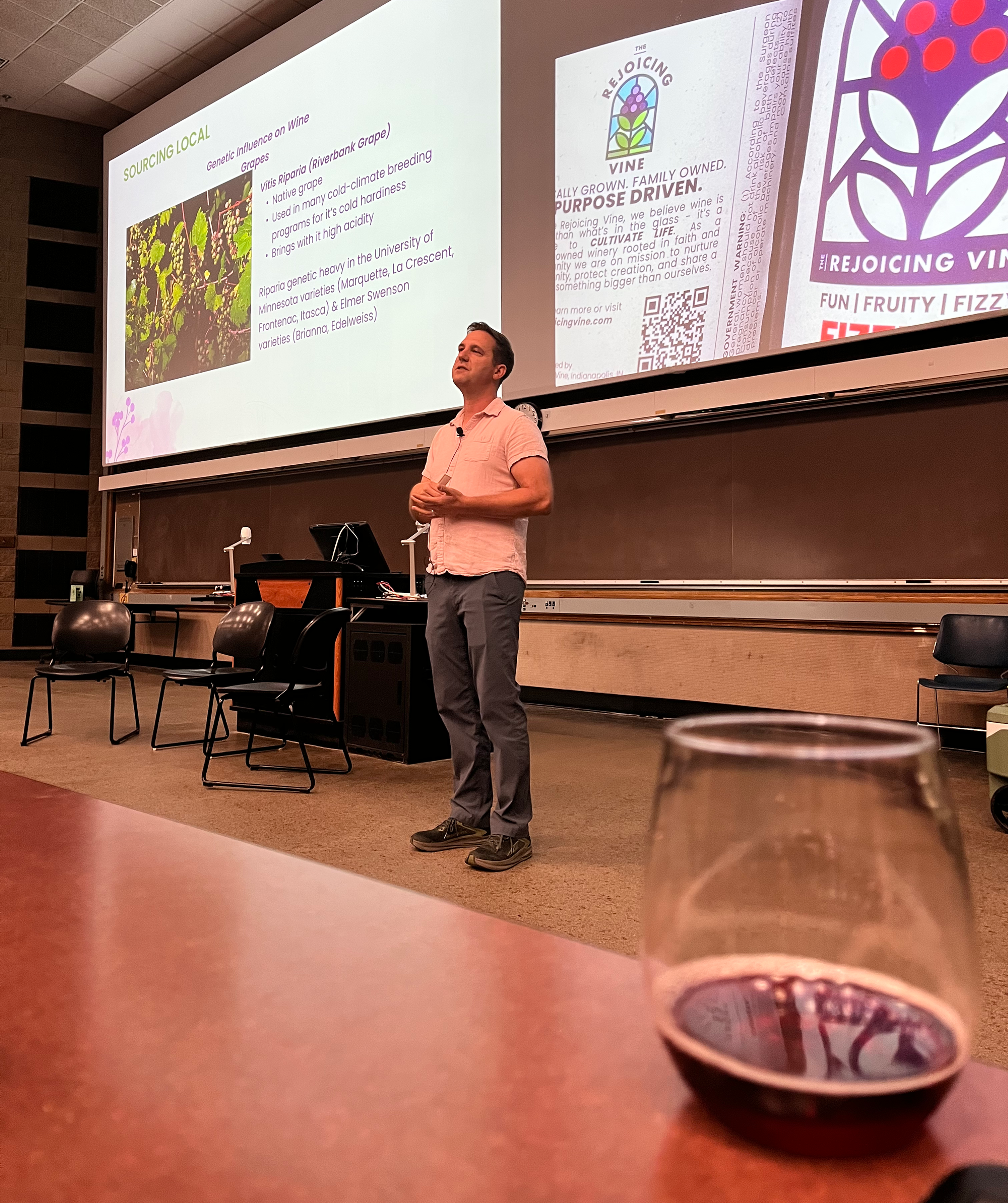 Brent Kumfer presenting on Indiana Wines in a classroom at Purdue, with projected slides about Rejoicing Vine and a wine glass in the foreground.