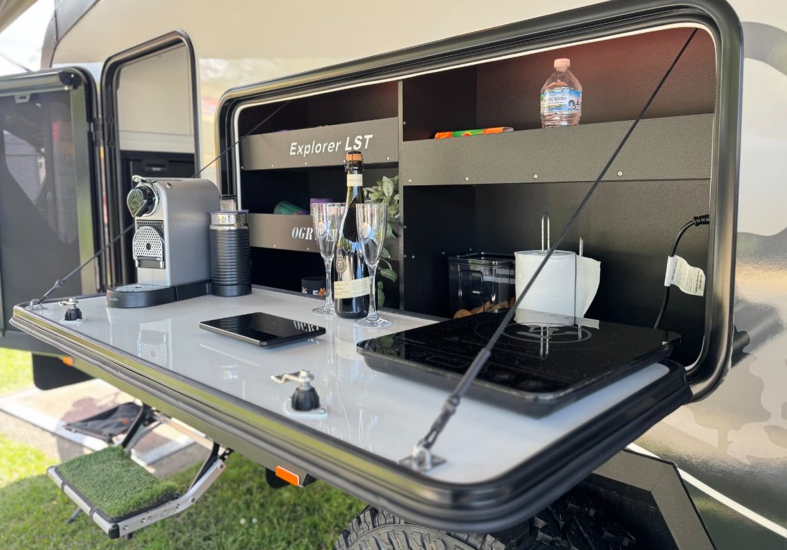 The fold-down outdoor kitchen and pantry open beside the entry door and pull-out step