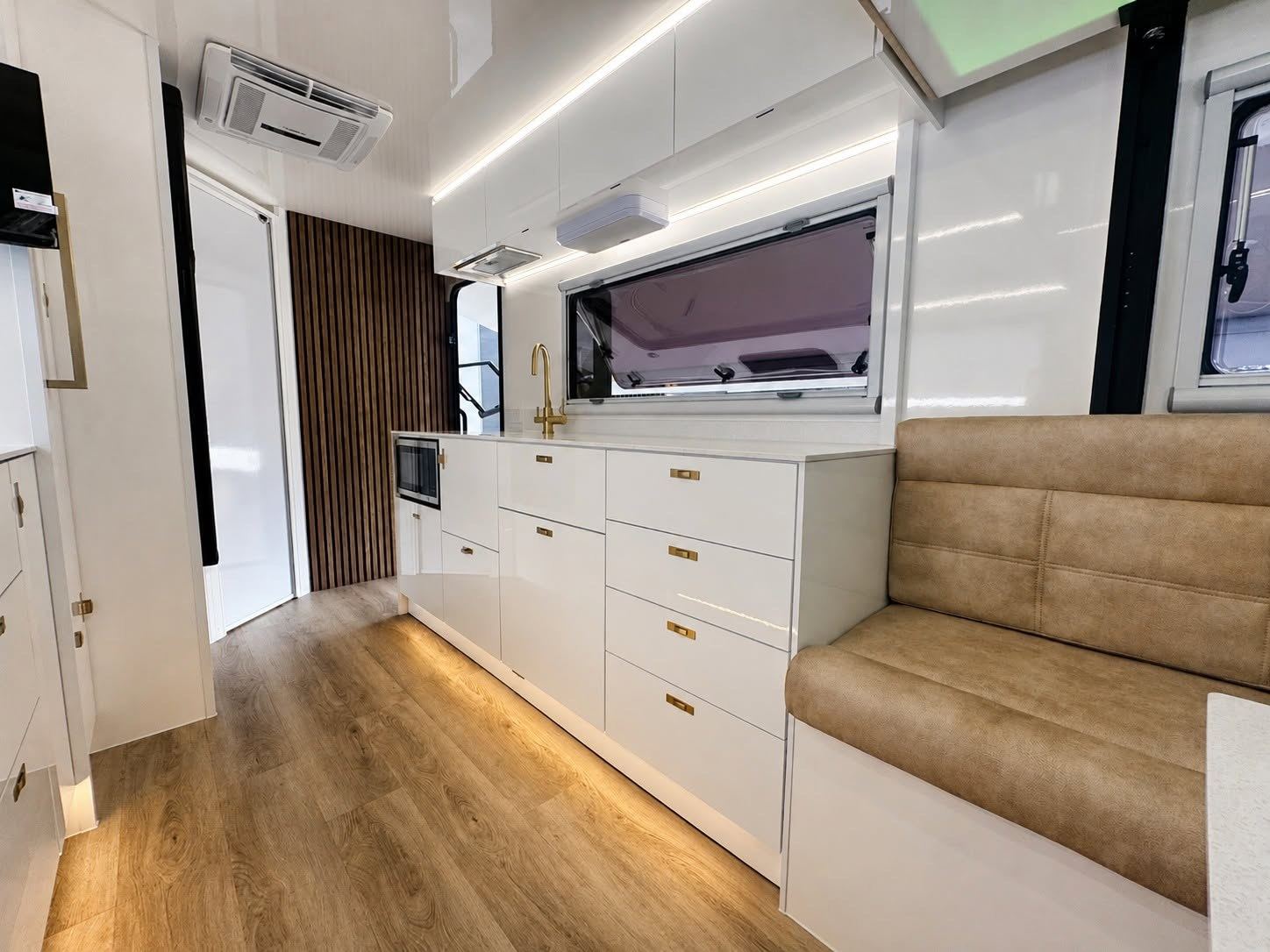 Kitchen with brass handles and a tan lounge