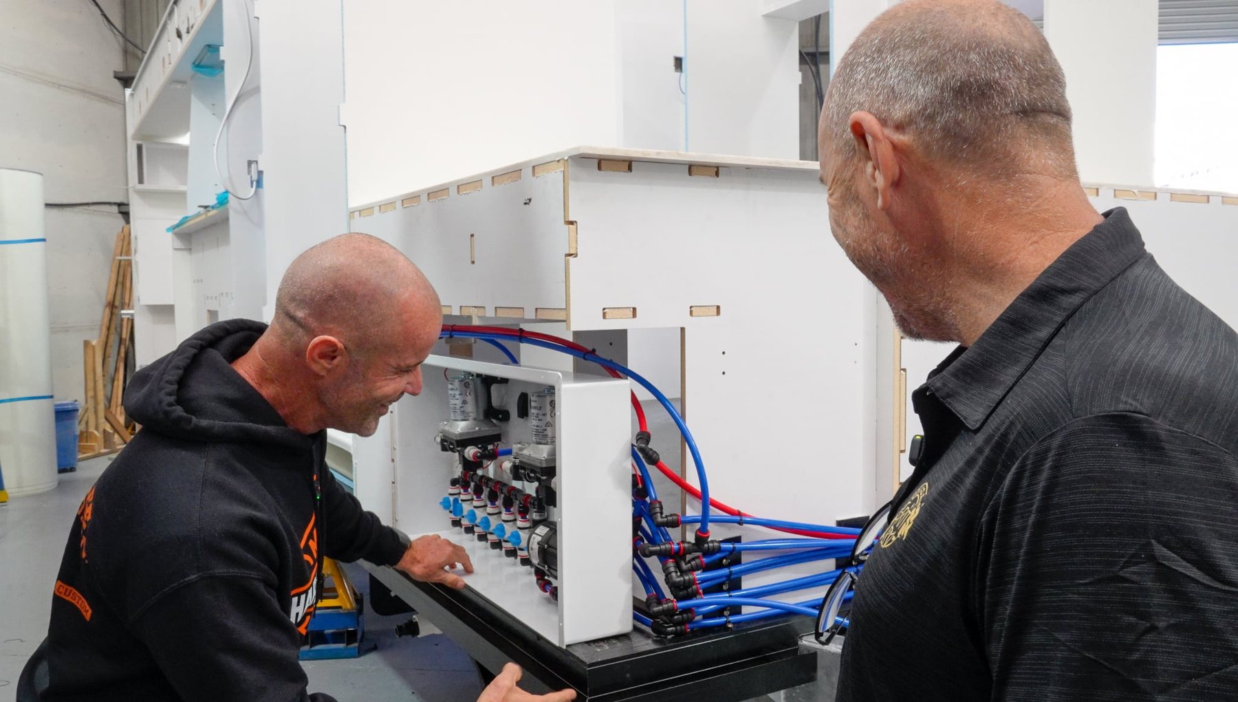 Two of the team checking a plumbing board