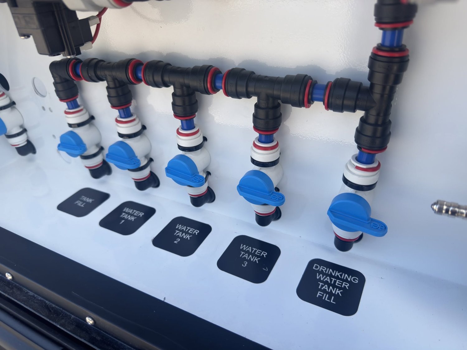 A plumbing box with a labelled tap for each water tank and fill