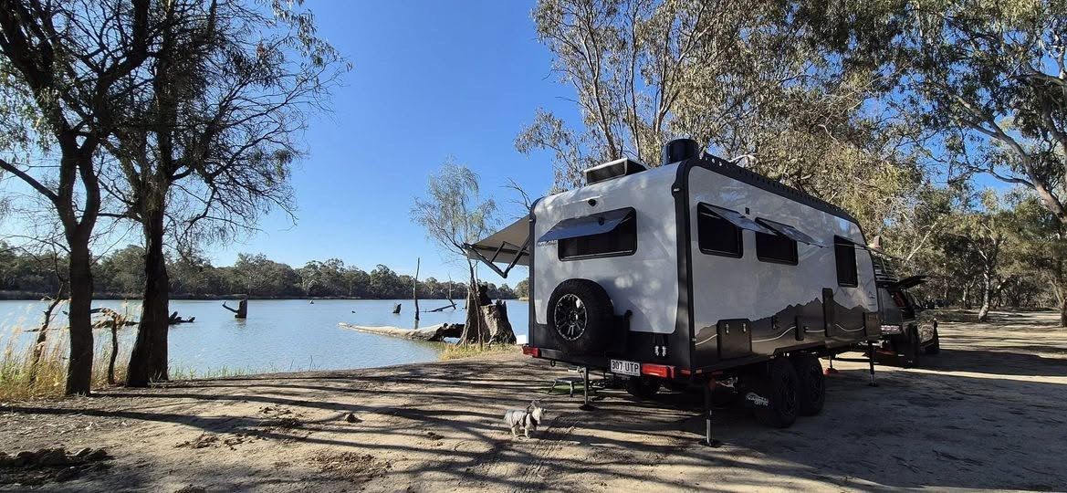 An Offroad Grit RV set up lakeside with the awning out