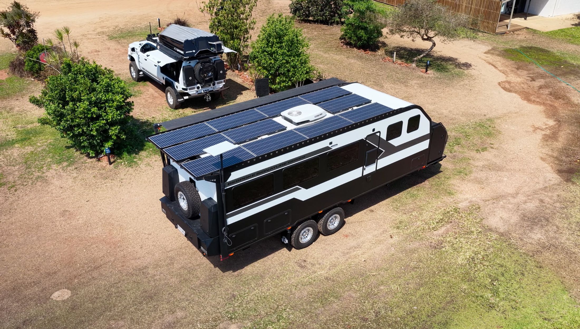 An Offroad Grit RV with solar across the roof and its ute, from the air