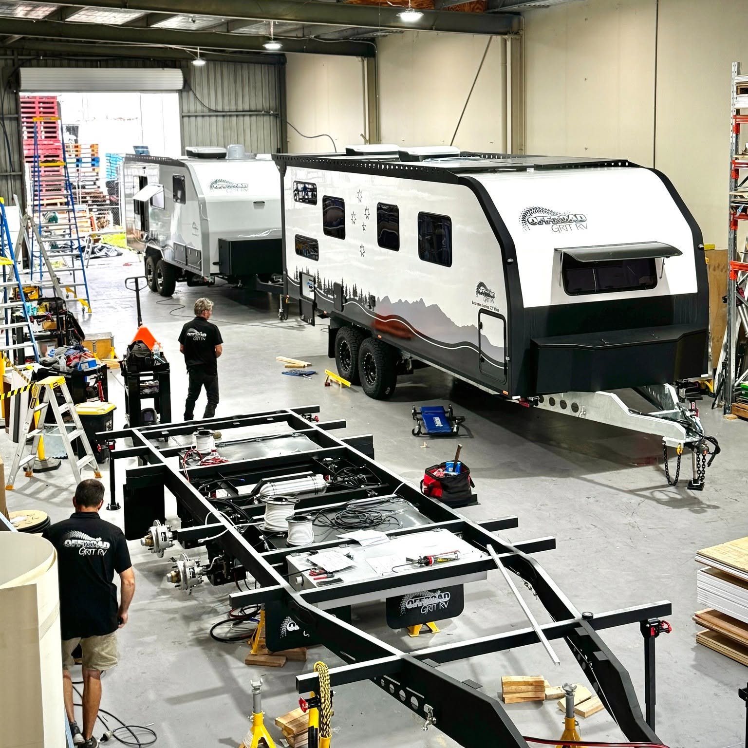 Inside our Caboolture factory: a chassis being fitted out in front of two finished vans