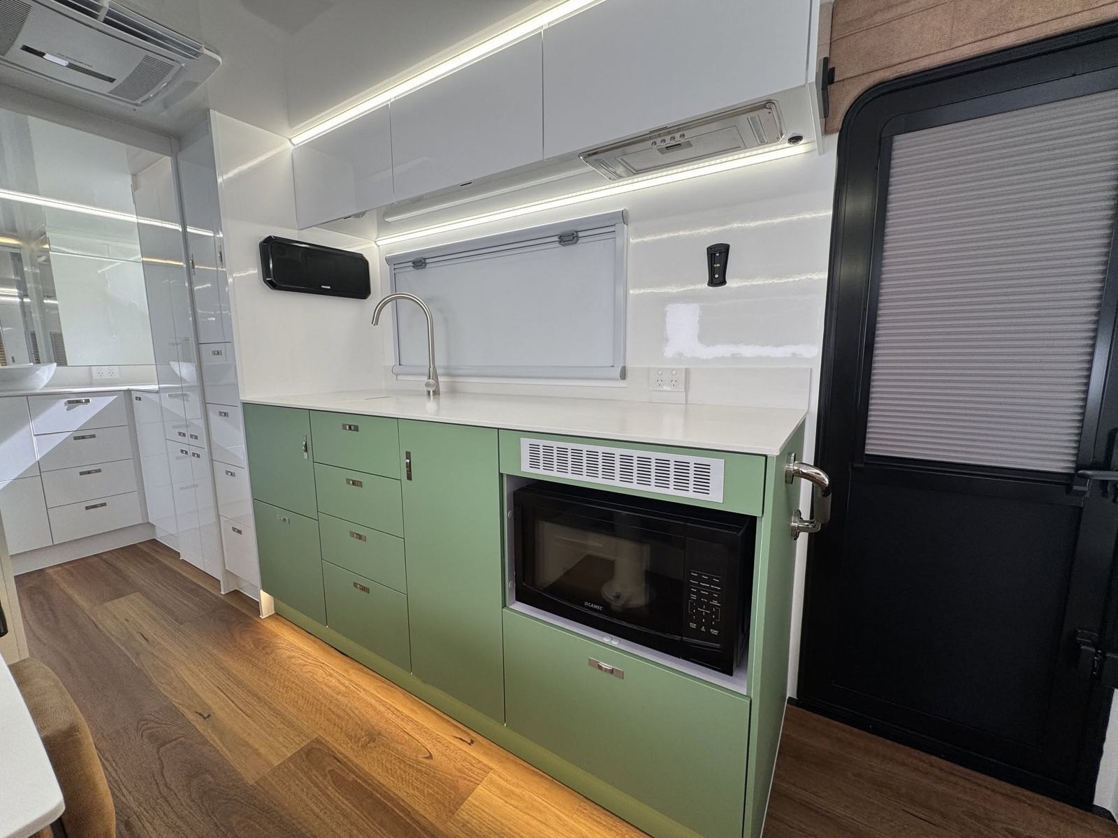 Green cabinetry with a microwave cut-in