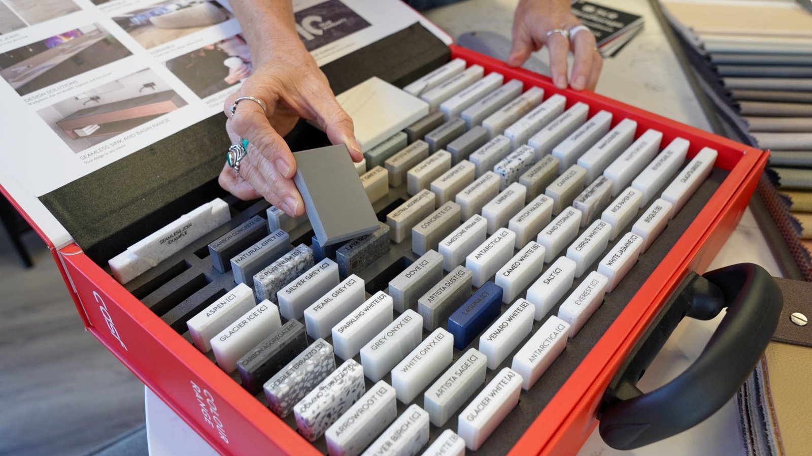 A customer picking a benchtop colour from a case of Corian samples